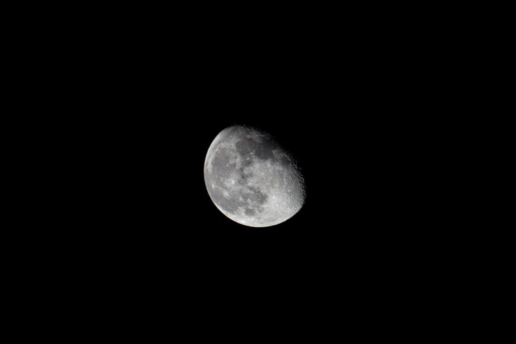 A detailed view of the waning gibbous moon set against a dark black sky.